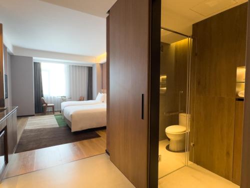 um quarto de hotel com uma cama e um WC em Paradiso Jiamusi em Jiamusi