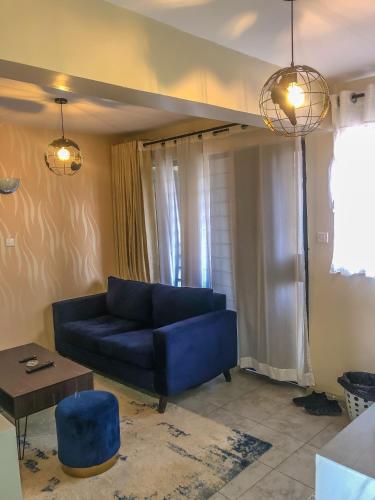 ein Wohnzimmer mit einem blauen Sofa und einem Tisch in der Unterkunft Harmony Condo in Nairobi