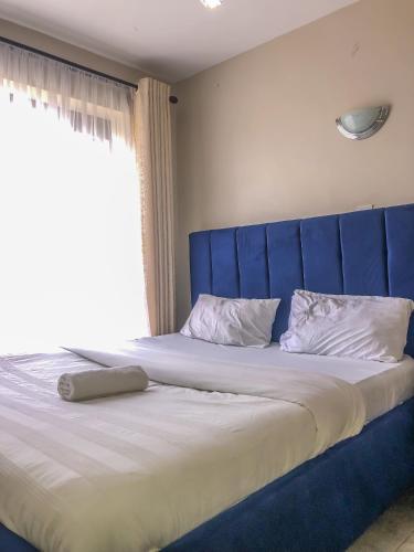 ein großes Bett mit blauem Kopfteil in einem Schlafzimmer in der Unterkunft Harmony Condo in Nairobi
