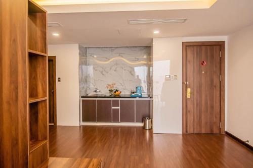 a living room with a wooden door and a kitchen at Gold Central Hotel by Haviland in Da Nang