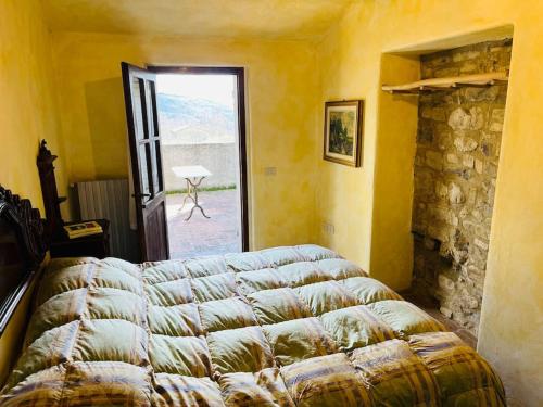 モントーネにあるAppartamento nel castello del cardanetoのベッドルーム1室(ベッド1台付)、パティオへのドアが備わります。