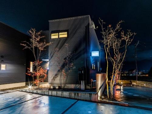 a building at night with trees in front of it at Rakuten STAY HOUSE x WILL STYLE Yufuin Kawakami in Yufu