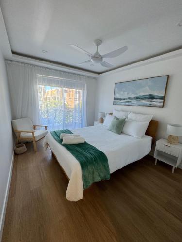 a bedroom with a large white bed and a window at Pelican Cove Apartments in Gold Coast