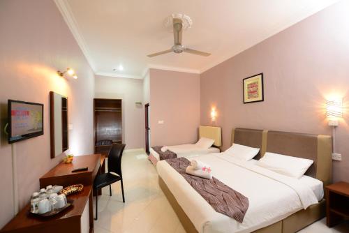 a hotel room with two beds and a desk at White Lodge in Pantai Cenang