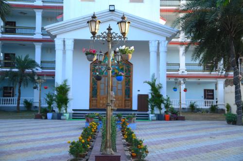 un edificio con una luz de la calle y flores delante de él en Hotel Harsh Garden en Begusarai