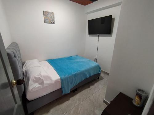a small bedroom with a bed and a flat screen tv at Apartaestudio Mali's House in Dosquebradas