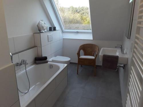 Baño blanco con bañera y lavamanos en Nice holiday apartment in Ostbevern, en Ostbevern
