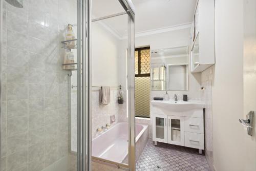 a bathroom with a shower and a tub and a sink at The Entertainer #2 in Perth