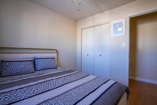 1 dormitorio con 1 cama con sábanas azules y blancas en Beautiful 5 BDRM Home, Fenced Yard, WiFi, Fireplace, Free Parking, Transit, Town Centre - Sleeps 12 en Edmonton