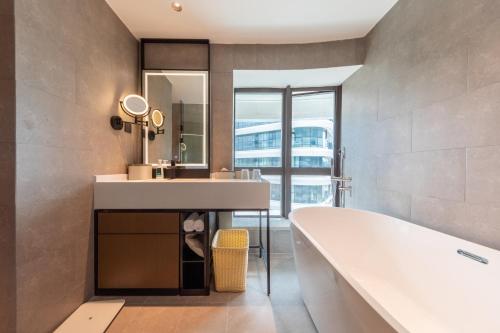 een badkamer met een bad, een wastafel en een spiegel bij Atour Hotel Zhaoqing Qixingyan in Zhaoqing