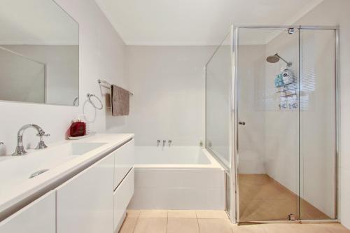 Henley Beach SouthにあるHenley Hideawayのシャワーと洗面台を備えた白いバスルーム