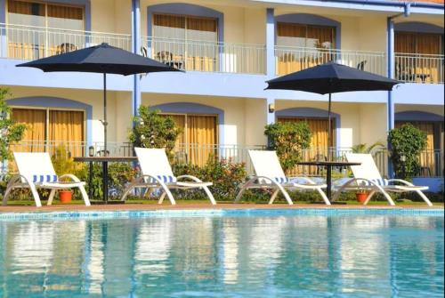 a hotel with a swimming pool with chairs and umbrellas at Baywatch Resort, Colva Goa in Colva