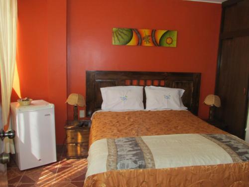 a bedroom with a bed with an orange wall at BRISAS DE LA BAHIA HOTEL in Paracas
