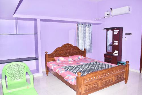 a bedroom with a wooden bed and a green chair at Sri Annamalaiyar Guest House in Tiruvannāmalai