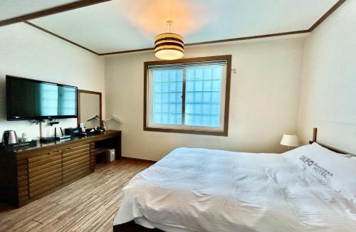 a bedroom with a bed and a flat screen tv at Okpo business hotel in Geoje