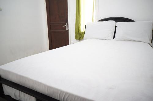 een bed met witte lakens en kussens in een kamer bij OYO 93785 Aero Kost Bu Lisa Syariah in Lawang