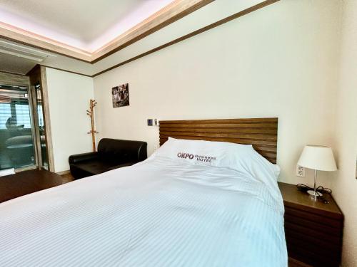 a bedroom with a large white bed and a chair at Okpo business hotel in Geoje 