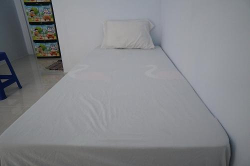 a white bed with a pillow on top of it at SPOT ON 93786 Kost Alamku Syariah 