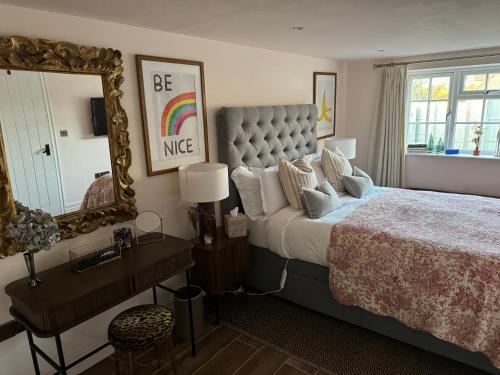 ein Schlafzimmer mit einem großen Bett und einem Spiegel in der Unterkunft Cotswolds Cottage 5min from Soho Farmhouse in Chipping Norton
