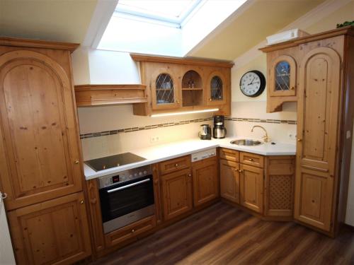 a kitchen with wooden cabinets and a clock on the wall at Landhaus Tröber in Grän
