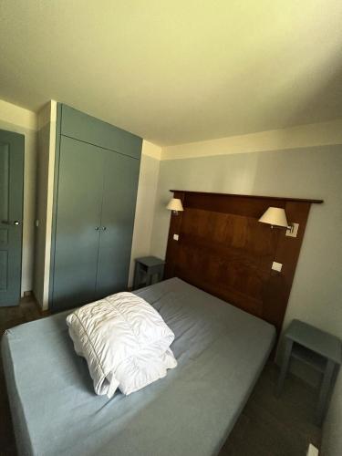 - une chambre avec un lit doté de draps blancs et d'une tête de lit en bois dans l'établissement Résidence La Marelle et Le Rami - maeva Home - 2 Pièces 5 Personnes Confort MAE-0757, à La Plagne Tarentaise