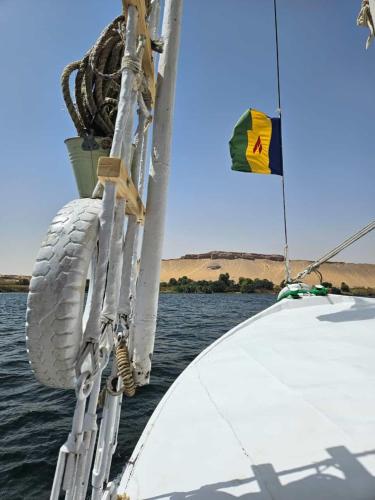 a white boat with a flag on the water at Felucca Sailing Boat Overnight Experience in Aswan