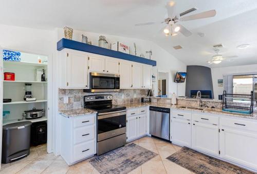 a kitchen with white cabinets and a stove top oven at HavaMemorable Stay Pool Spa Firepit VIEWS! in Lake Havasu City