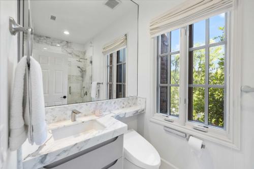 a white bathroom with a sink and a window at @ Marbella Lane - 4BR Mediterranean-style Home in Newport Beach