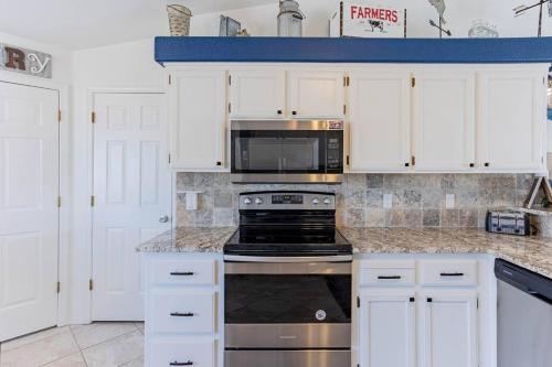 a kitchen with white cabinets and a stove top oven at HavaMemorable Stay Pool Spa Firepit VIEWS! in Lake Havasu City