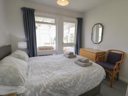 a bedroom with a bed and a chair and a mirror at Hafod-y-Gors in Fairbourne
