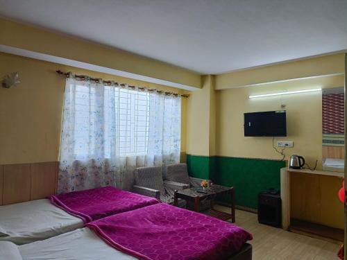 a bedroom with a bed and a chair and a window at LHONARK RESIDENCY in Gangtok