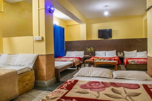 um quarto com quatro camas e uma televisão na parede em LHONARK RESIDENCY em Gangtok
