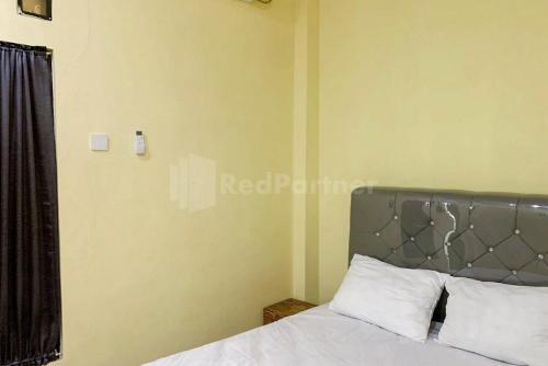 a bedroom with a bed with a silver headboard at Asyura Kostel Syariah Redpartner in Kedaton