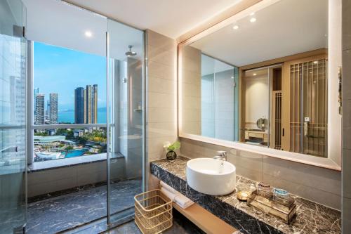 baño con lavabo y espejo grande en Kyushu Joycheng Hotel, en Shenzhen