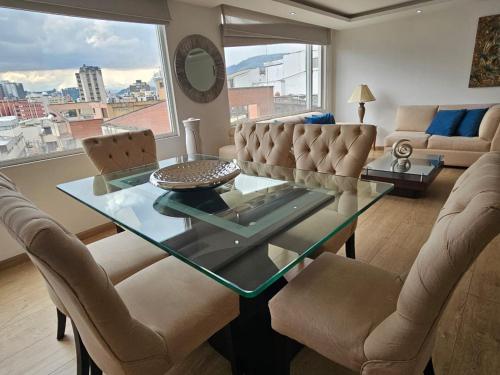 a living room with a glass table and chairs at Confortable, moderno y hermoso departamento. in Quito
