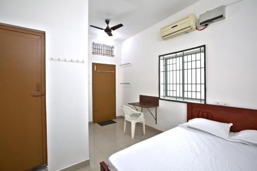 a bedroom with a bed and a desk and a window at Sarvam Lodge in Pīlamedu