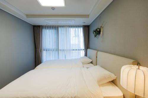 two beds in a small room with a window at Wecostay Gangnam in Seoul