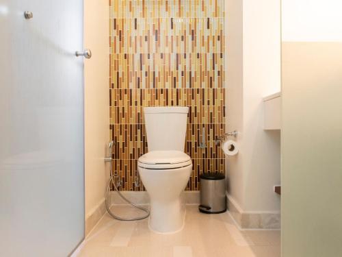 a bathroom with a toilet with a tiled wall at Holiday Inn Express Phuket Patong Beach Central by IHG in Patong Beach