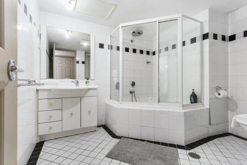 y baño blanco con ducha, bañera y lavamanos. en 2-Bed Unit with Balcony BBQ & Stunning Lake Views, en Belconnen