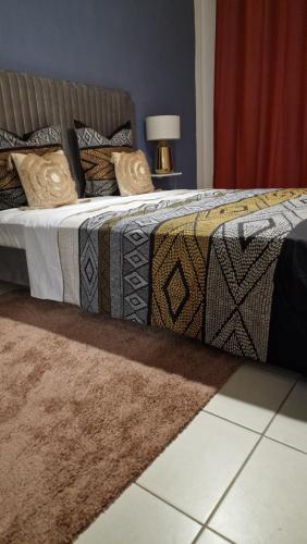 uma cama com um edredão e almofadas em Prestige Spa Cayenne T2 em Cayenne