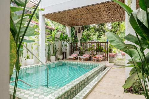 an outdoor swimming pool with a pergola and patio furniture at Naia Lombok in Kuta Lombok
