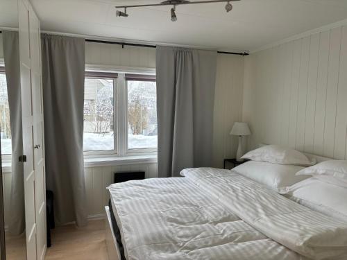 ein weißes Schlafzimmer mit einem Bett und einem Fenster in der Unterkunft Sentral 4-roms leilighet i Trollbakken in Tromsø