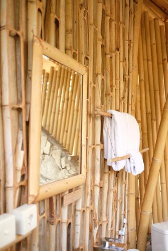 Maringi Sumba by Sumba Hospitality Foundation في Waikelo: مرآة ومنشفة معلقة على جدار الخيزران