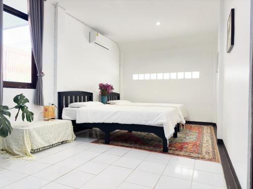 two beds in a white room with a rug at An‘s Home in Chiang Mai