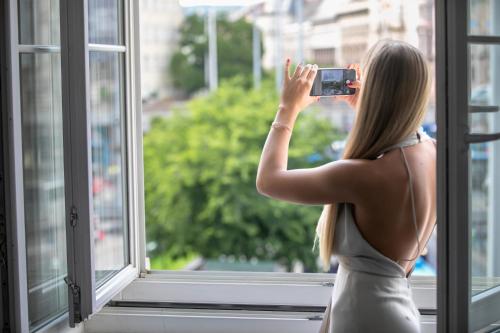 a woman taking a picture of a window at T62 Hotel in Budapest