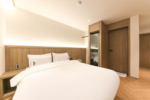 a bedroom with a large white bed and a closet at Hound Hotel Jeonju Deokjin in Jeonju