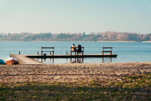 two people sitting on a dock on a lake at Glamping Mazury - Przystań Jeziorany in Jeziorany