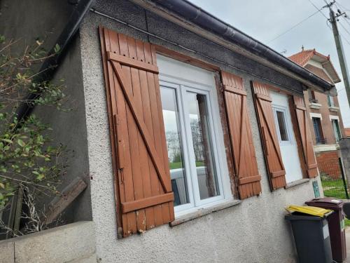 three windows with wooden shutters on a building at Road Stop Studio *Paris*Disney*Gare* in Chelles
