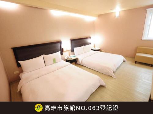 a hotel room with two beds and a chair at Kindness Hotel Weiwuying in Kaohsiung