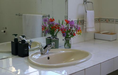 a bathroom with a sink and flowers in a mirror at Kairos on the Lake in Sedgefield